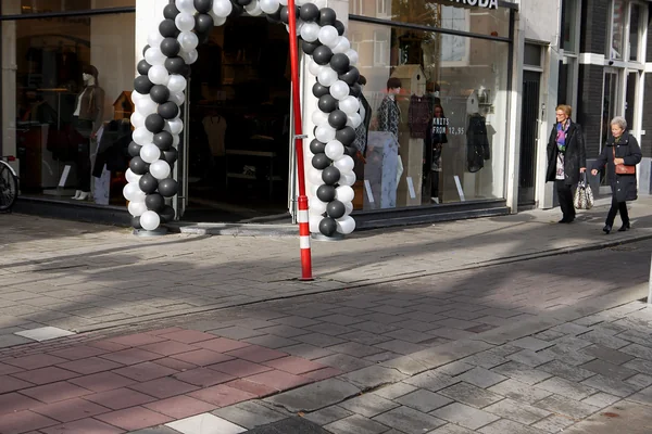Street life with clothing shop entrance and shopping women in the Ferdinand Bolstreet in sunlight and shadows and shop-entrance; photo Amsterdam city; urban photographer Fons Heijnsbroek, 2013