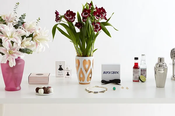purple phalaenopsis orchid in vase white and pink lilies chocolate and assorted truffles stainless steel cocktail drink mixer bar tools lime bitters necklace earrings ring jewelry perfume