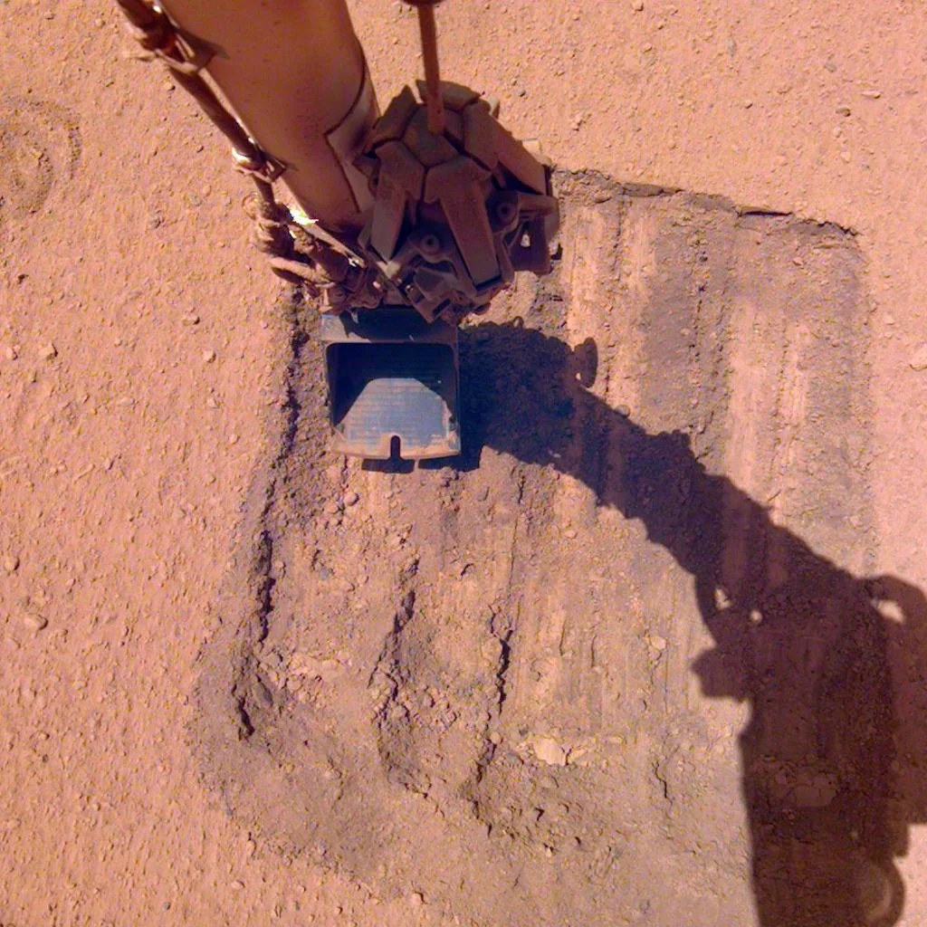InSight's Robotic Arm Helps Remove Solar Panel Dust Trickles Sand in the Wind